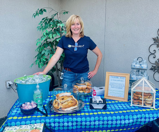 A woman standing next to a table with food on it.