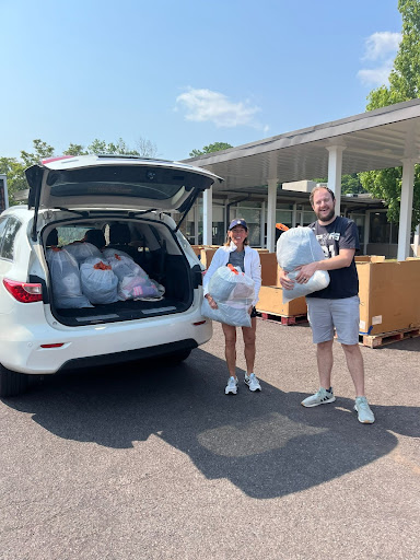 A man and woman standing next to the back of a car.